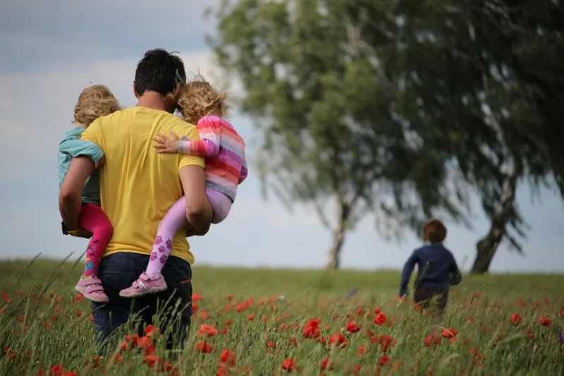 An adult and young children in a poppy field—care, protection, and the outdoors